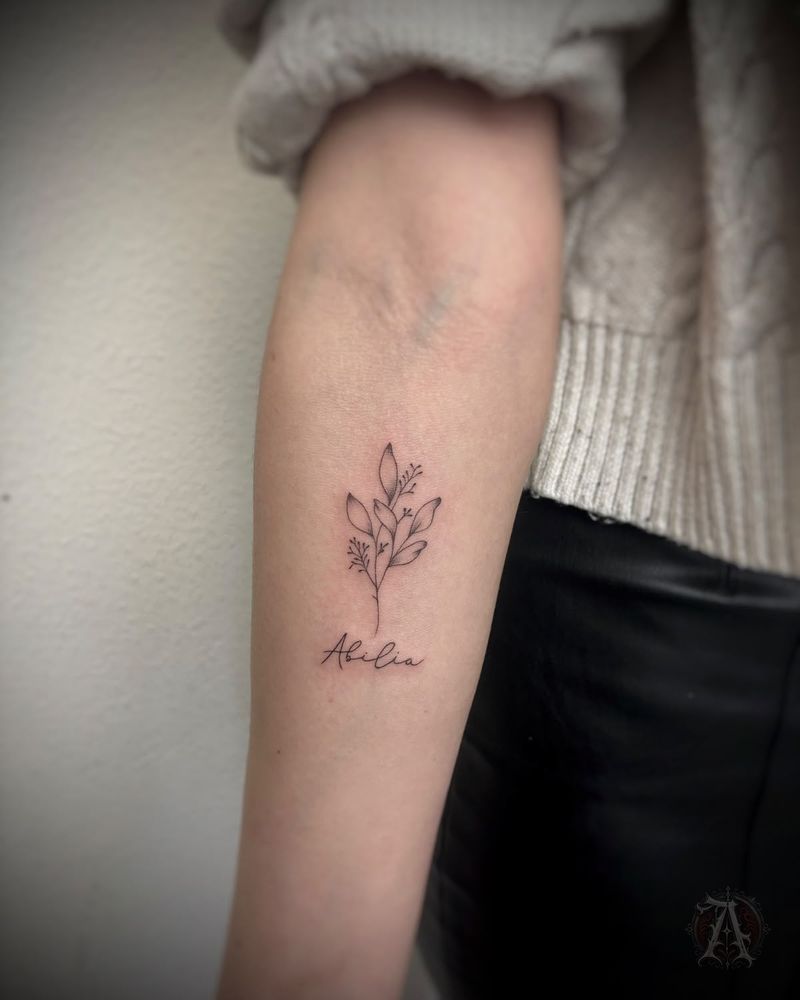 Tatuaje de rama y nombre manuscrito en el antebrazo, fine line en negro y gris